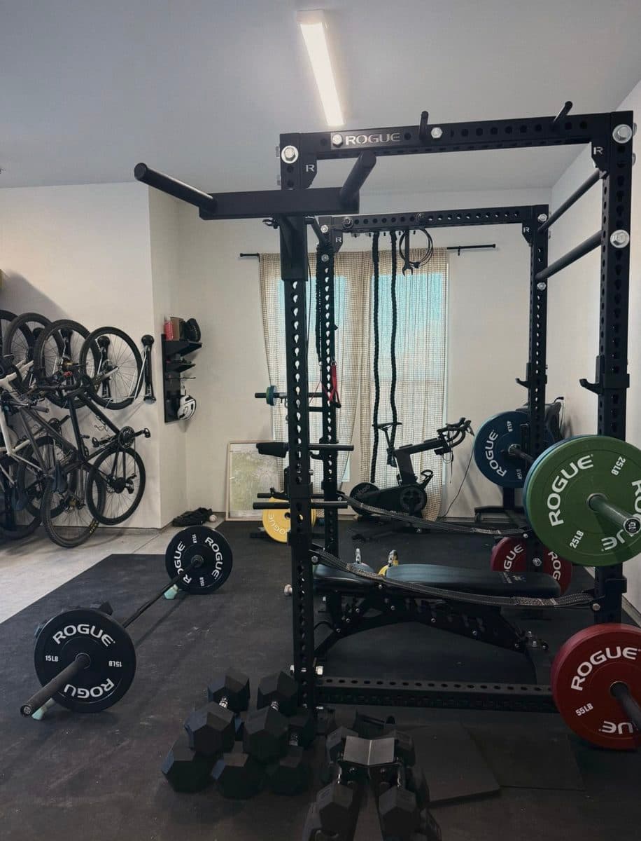 Home gym with a squat rack, plates, dumbbells, and bikes on the wall