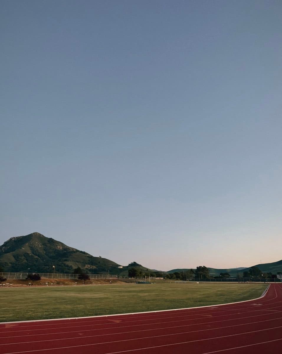 An empty running track under a mountain at dusk